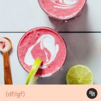Top down shot of two glasses of our blood orange smoothie recipe topped with a swirl of coconut milk