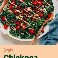 Wooden salad spoons on a tray of chopped kale salad with smoky chipotle dressing