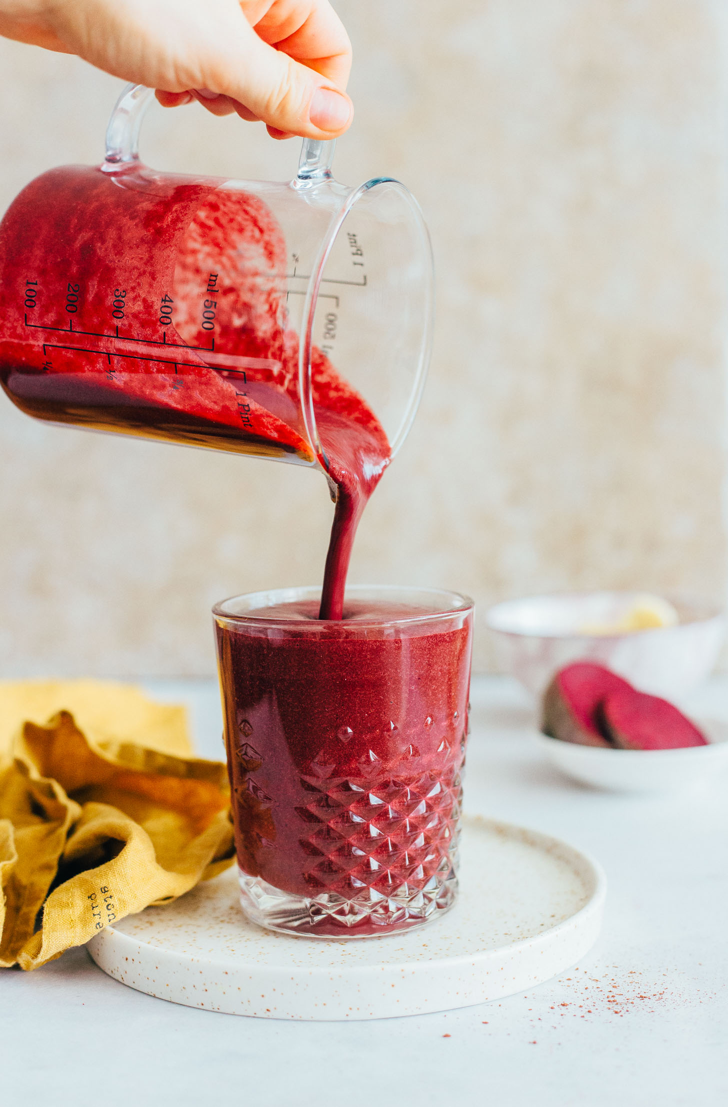 Pouring our Red Velvet Smoothie from a measuring glass into a drinking glass