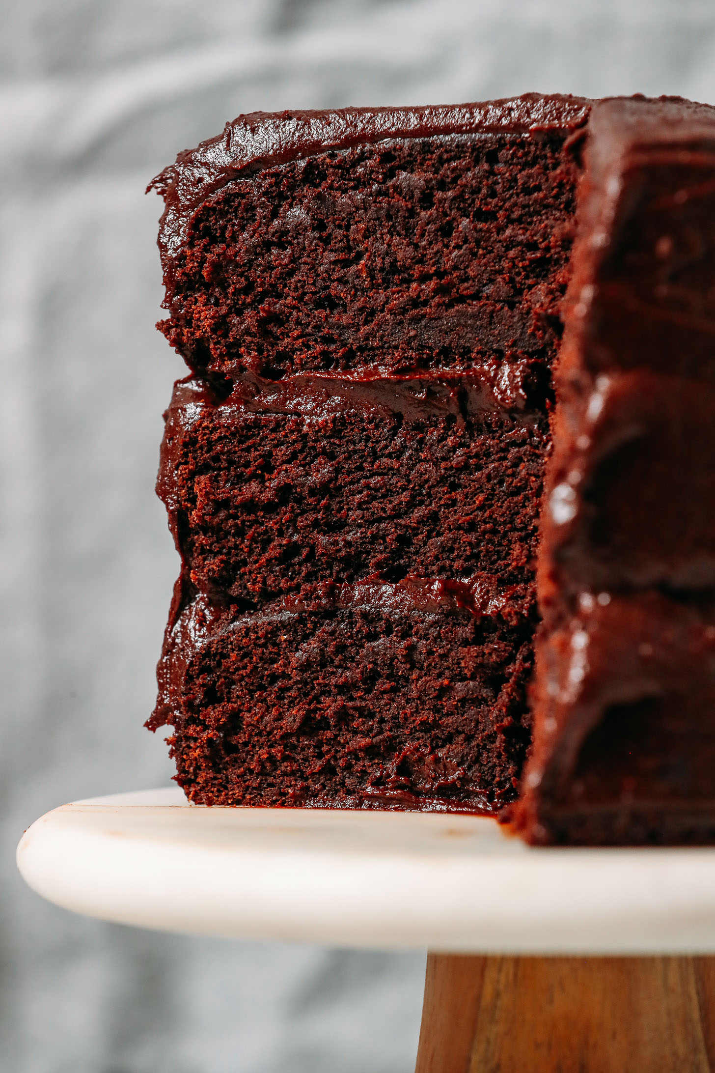 Close up shot of a slice of three layer Gluten Free Chocolate Cake with Vegan Chocolate Frosting