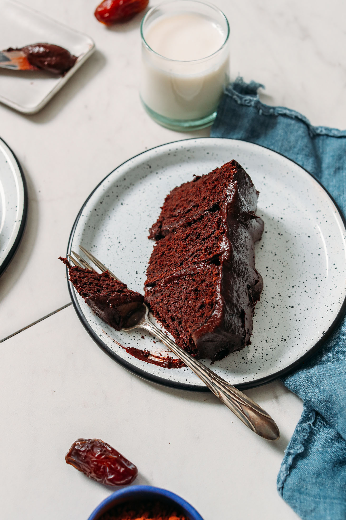 Glass of almond milk next to a plate with a slice of Dairy Free Gluten Free Chocolate Cake