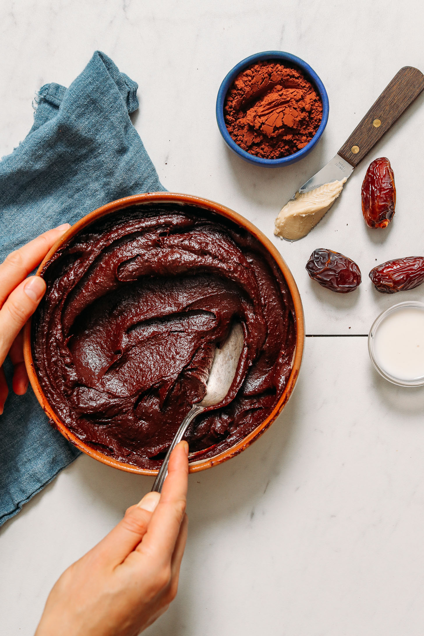 Holding a spoon and bowl of Vegan Chocolate Frosting