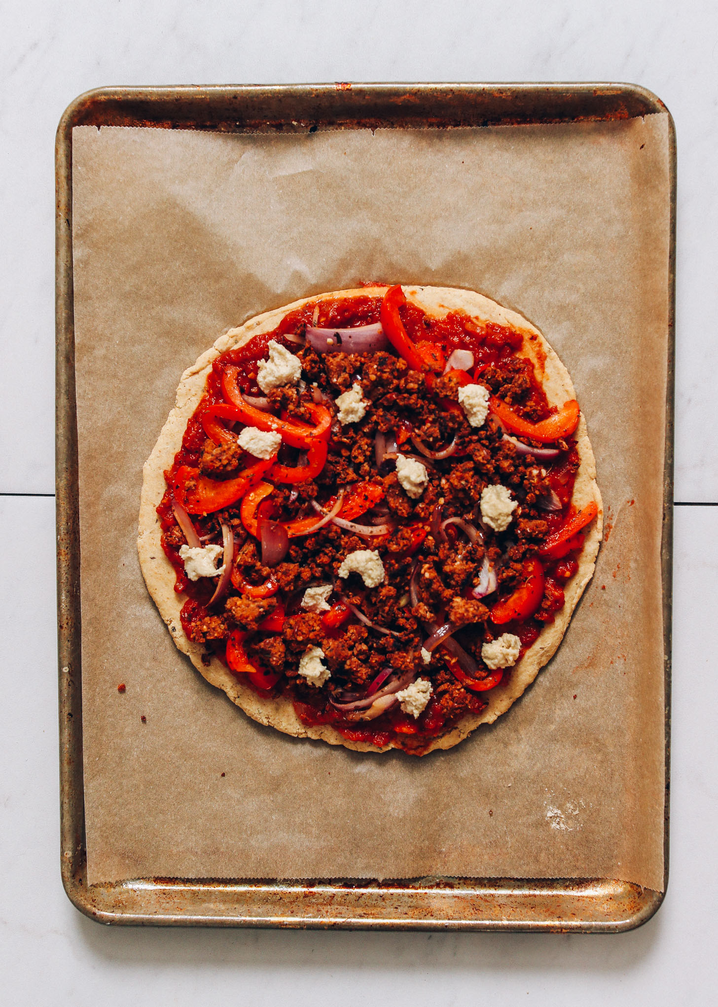 Vegan pizza on a baking sheet ready to go in the oven