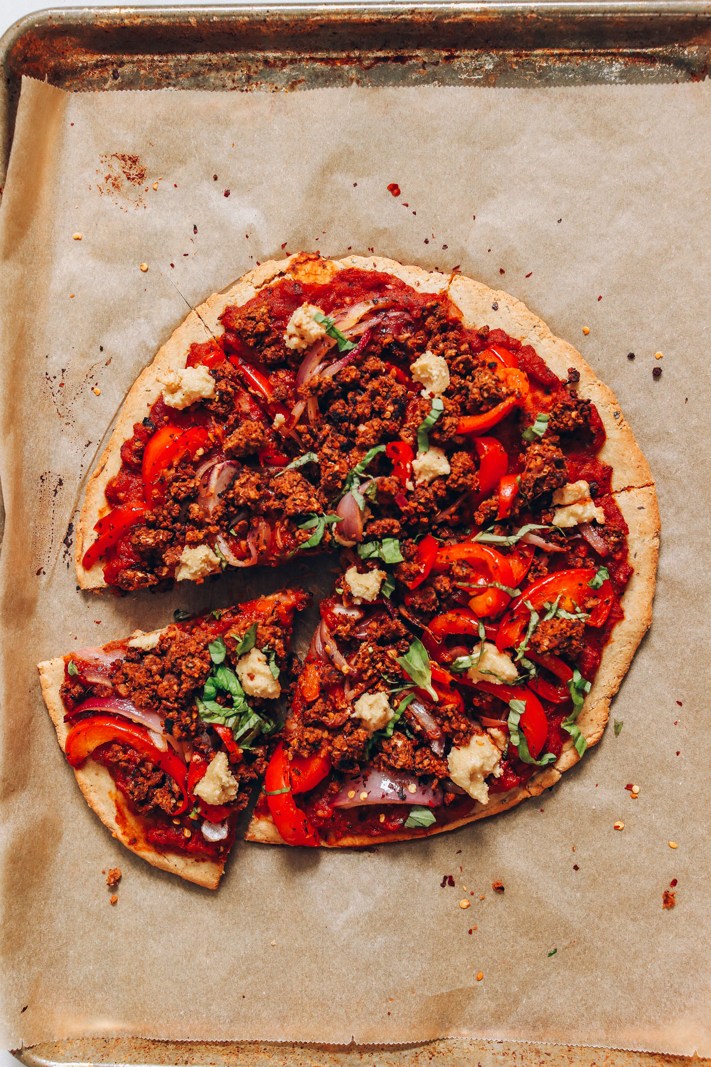 Veggie and Sausage Vegan Pizza on a parchment-lined baking sheet