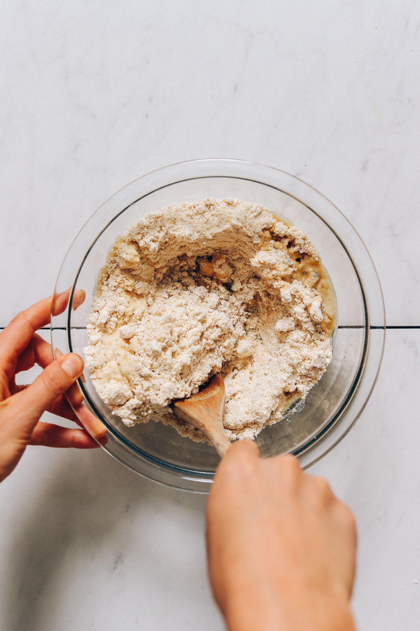 Using a wooden spoon to stir gluten-free pizza dough