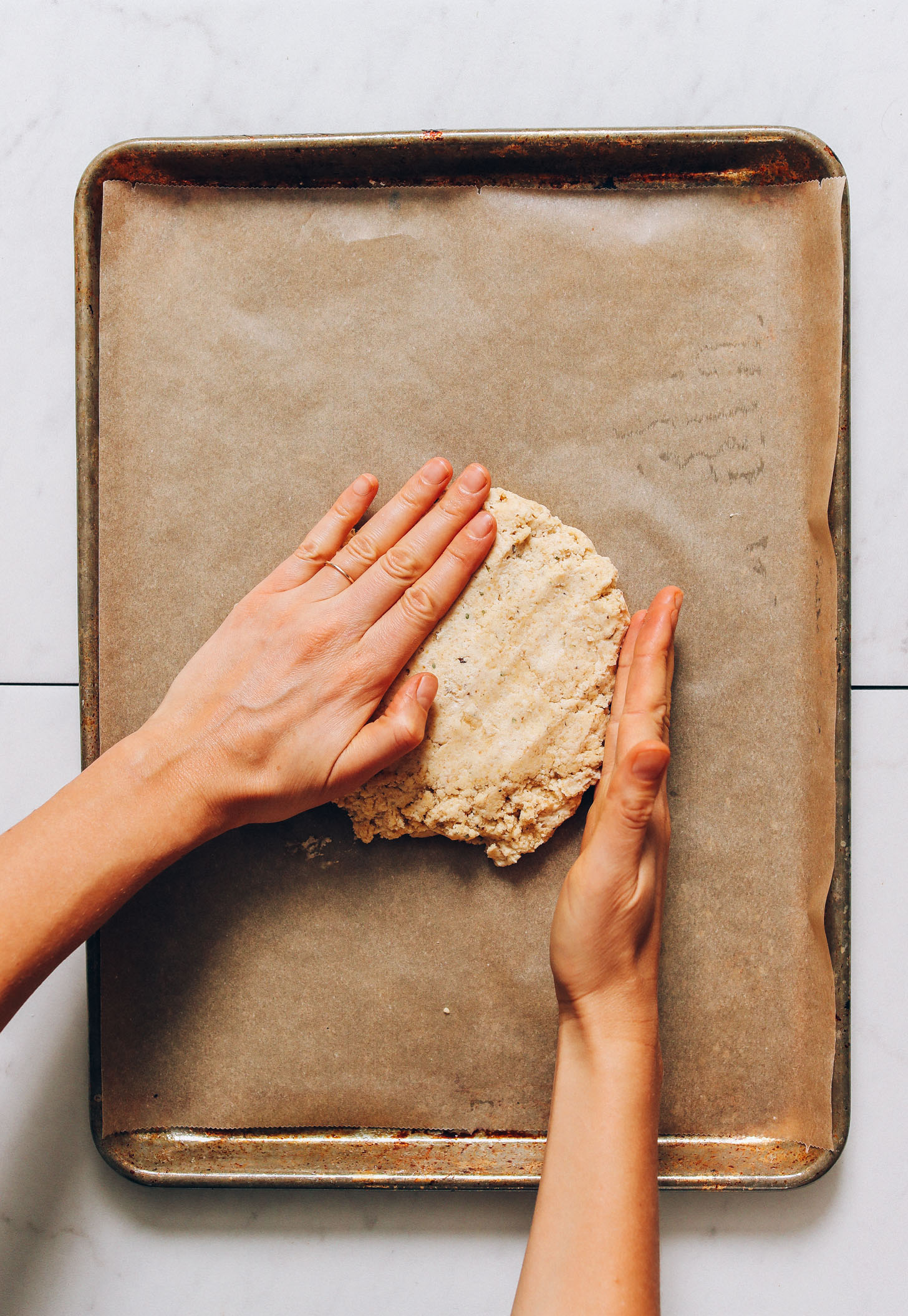 Shaping vegan gluten-free pizza dough on a baking sheet