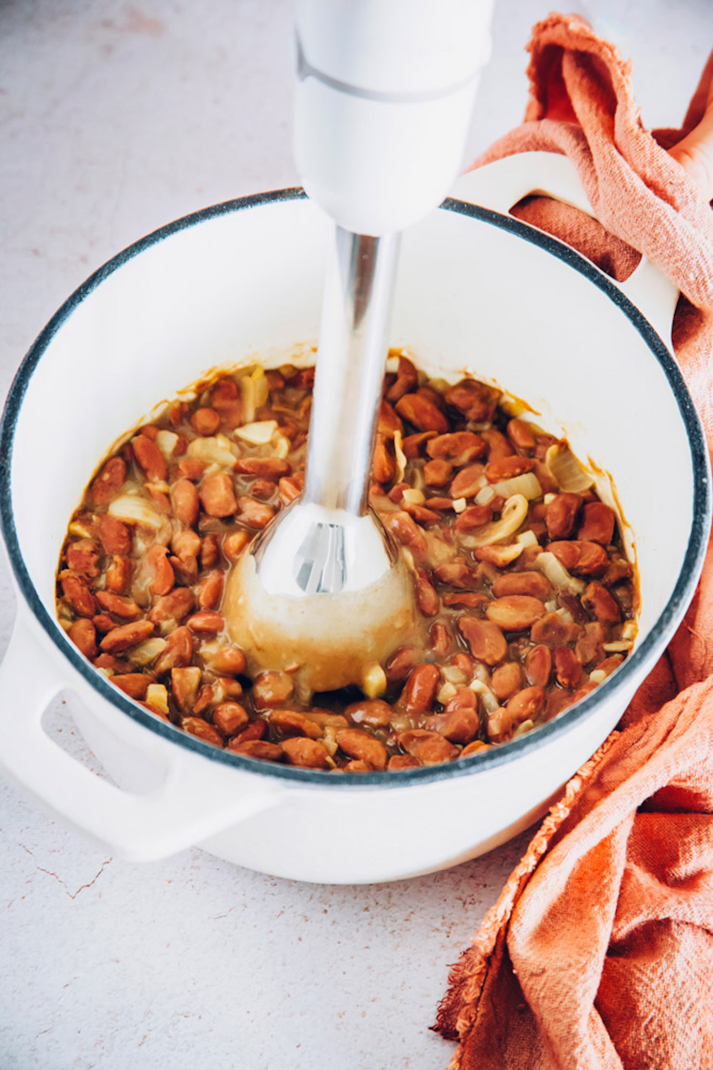 Using an immersion blender to puree a pot of pinto beans and seasonings