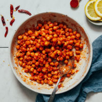 Bowl of Harissa Marinated Chickpeas next to lemons and spices
