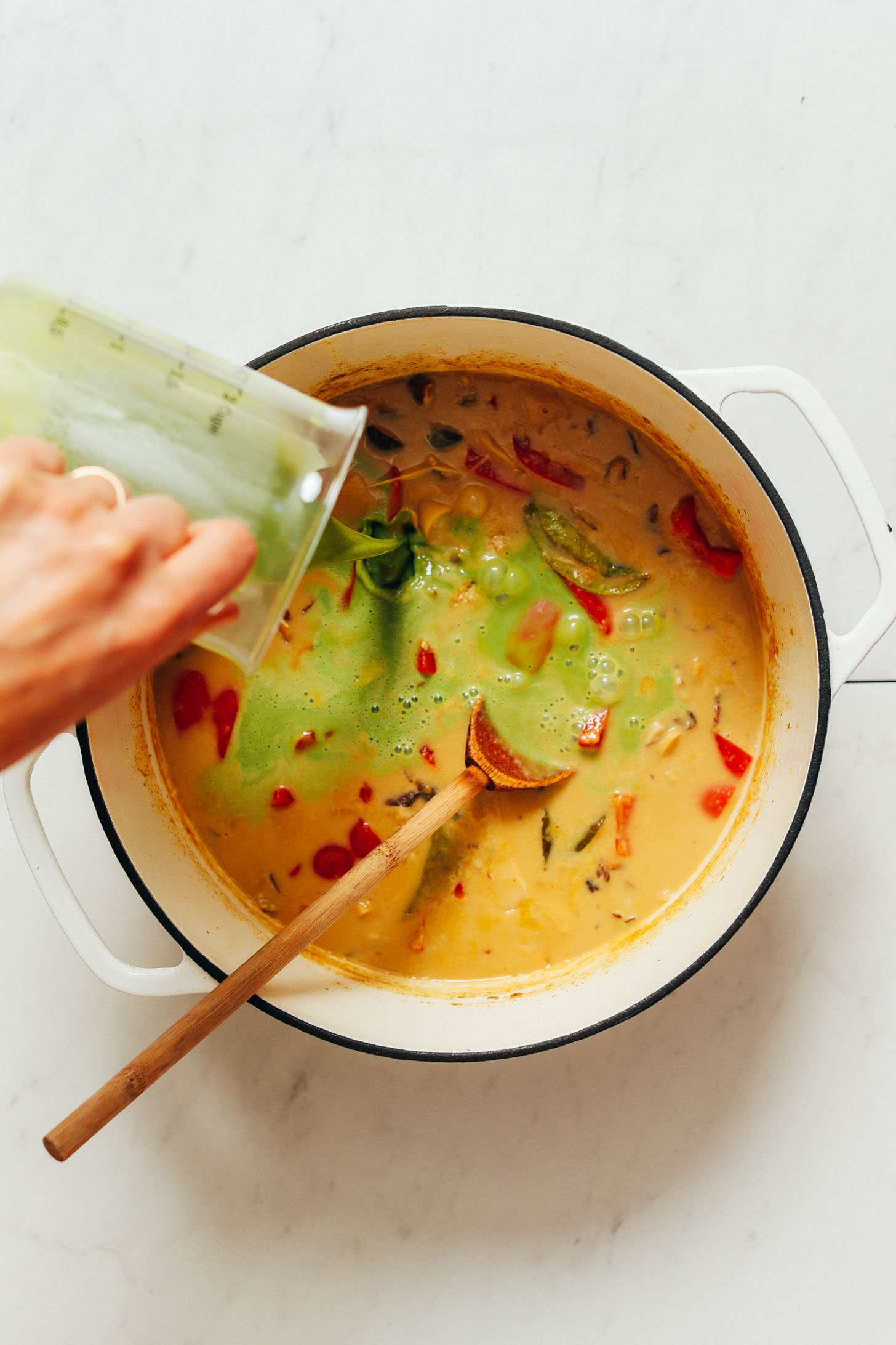 Pouring barley grass powder into a pot to make a more vibrant green curry color