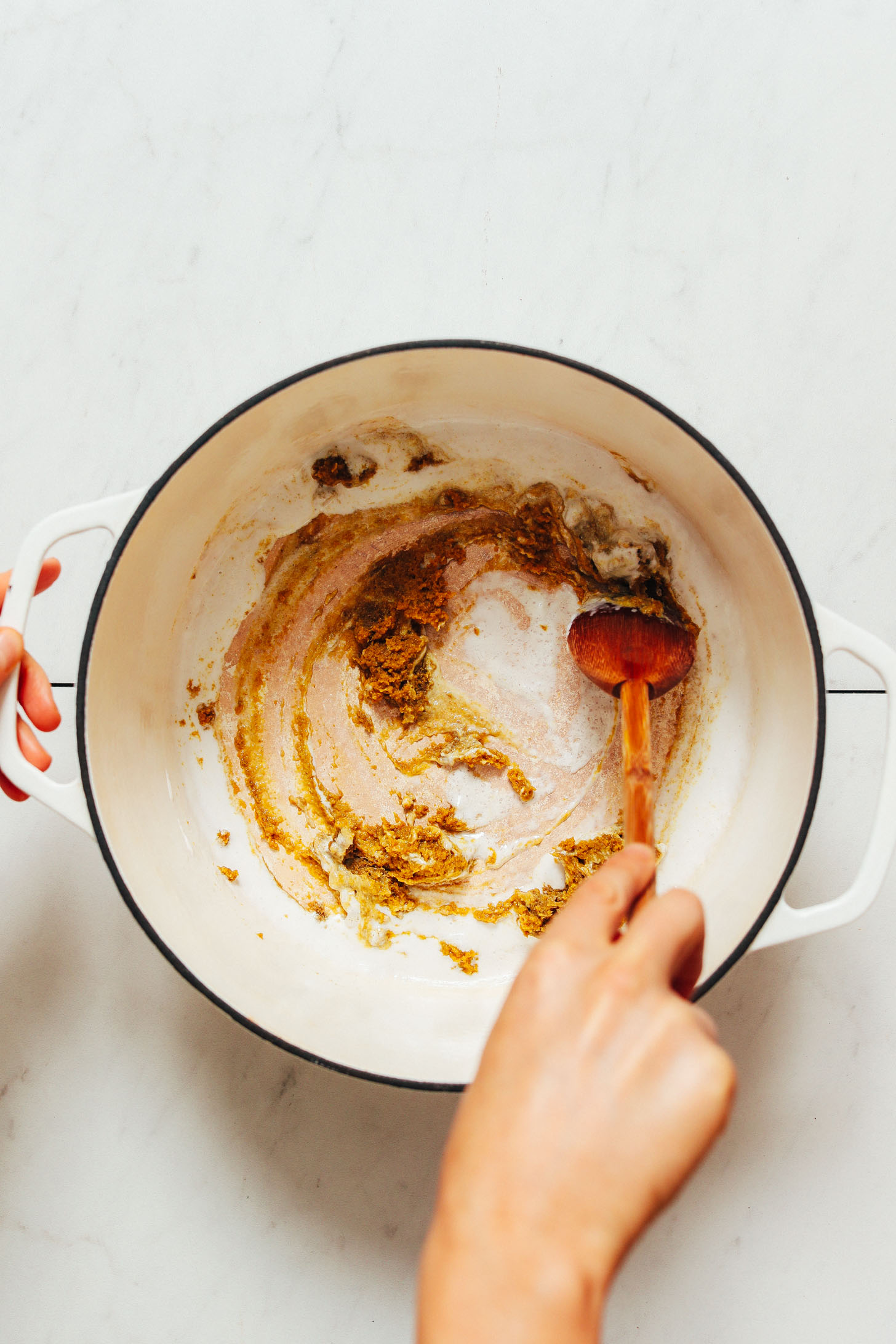 Stirring coconut milk and green curry paste in a pot as an oil-free trick