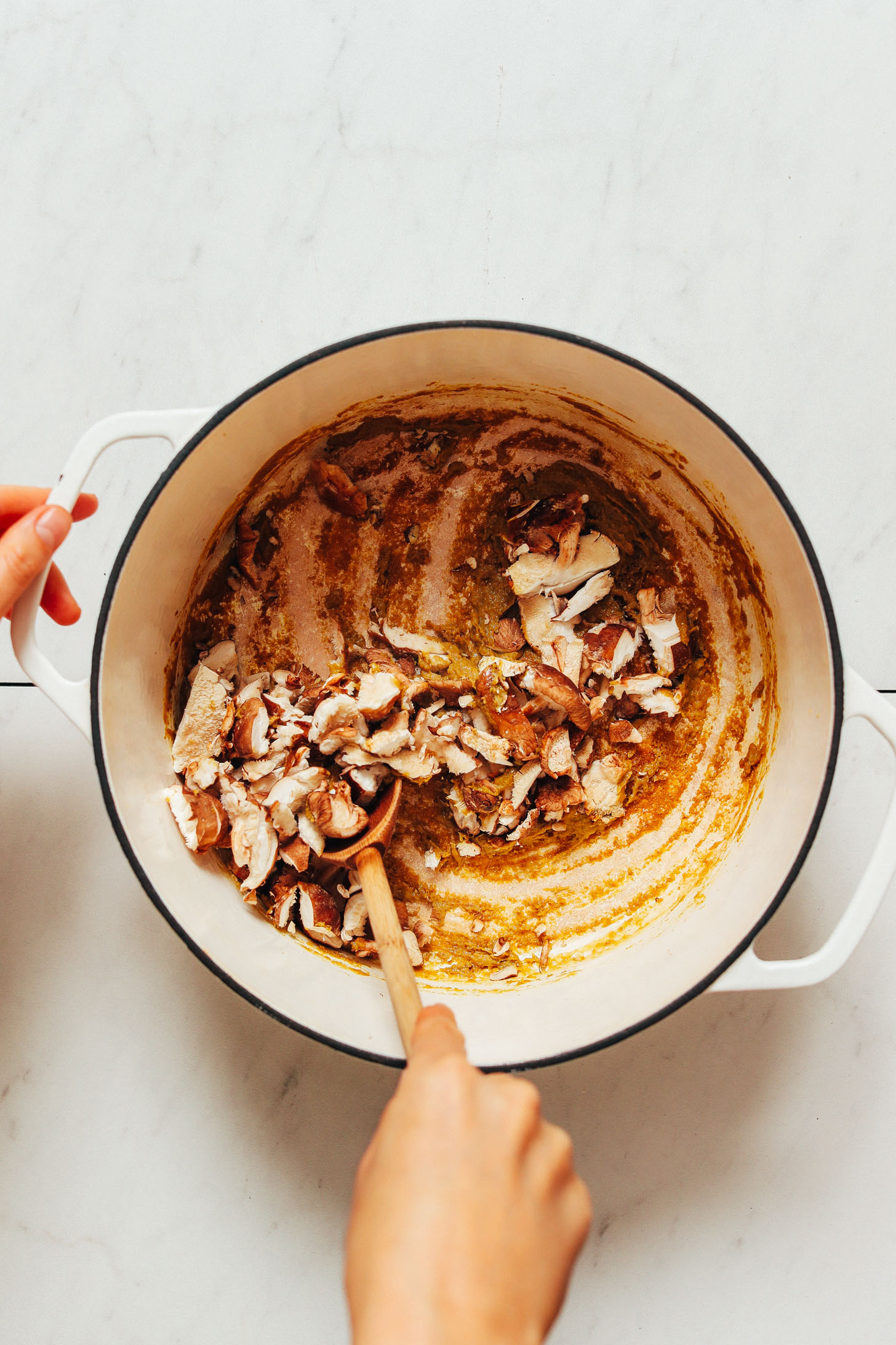 Stirring shiitake mushrooms into a coconut milk and green curry mixture