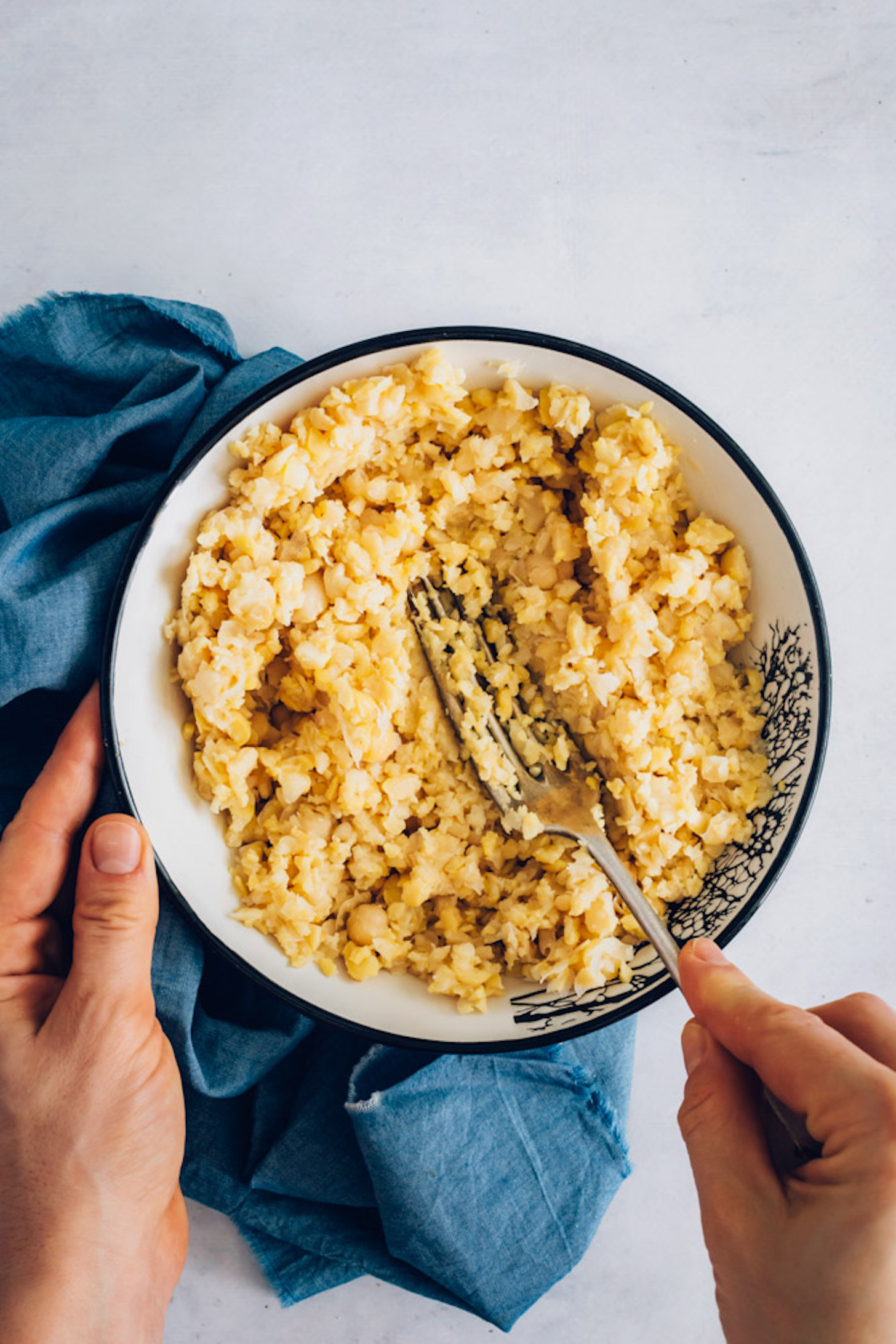 Using a fork to mash a bowl of canned chickpeas