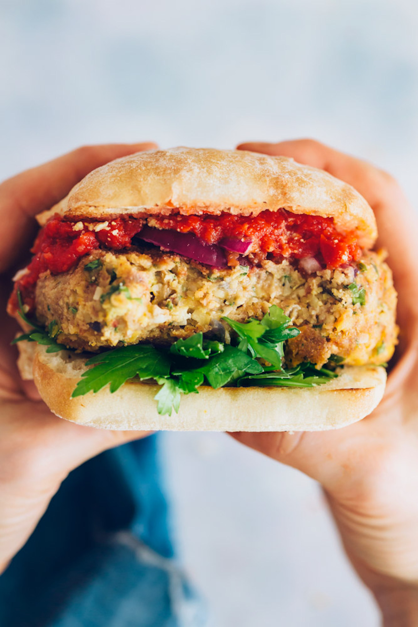 Close up shot of hands holding a Pizza Burger on a bun