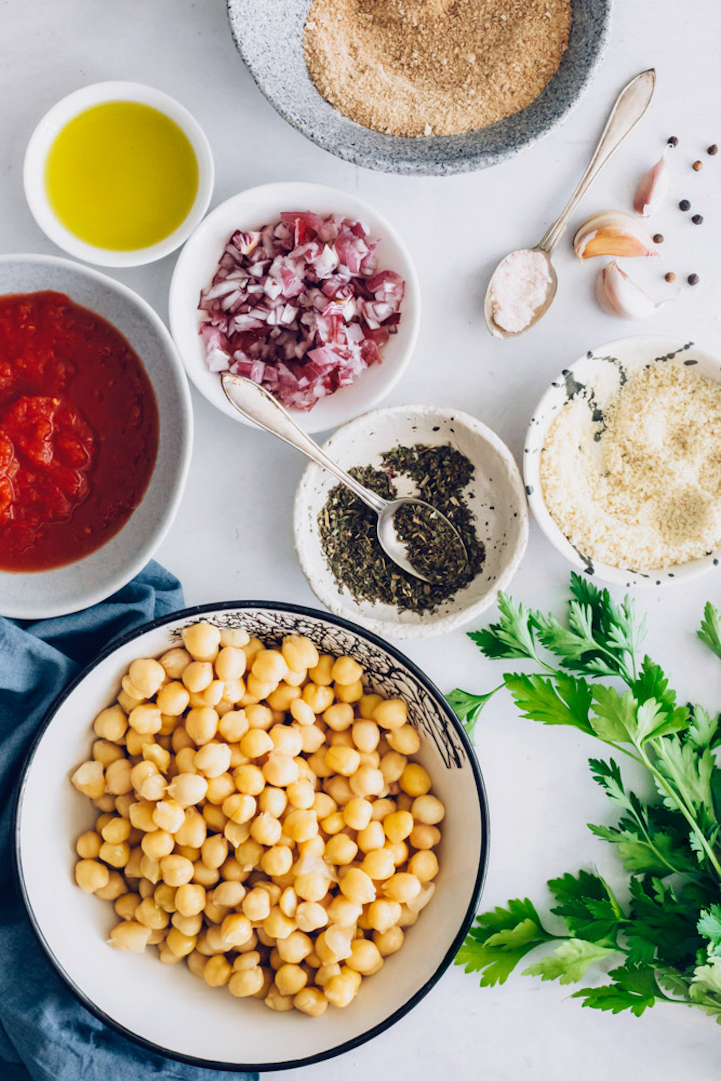 Bowls of chickpeas, Italian seasonings, red onion, vegan parmesan, breadcrumbs, salt, and olive oil