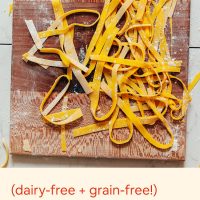 Strips of uncooked homemade gluten-free pasta on a wood cutting board