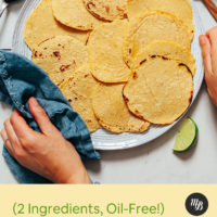 Holding the sides of a plate of homemade corn tortillas