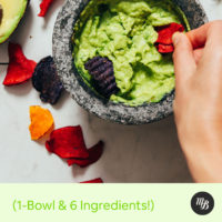 Dipping veggie chips into a mortar and pestle of serrano and rosemary guacamole