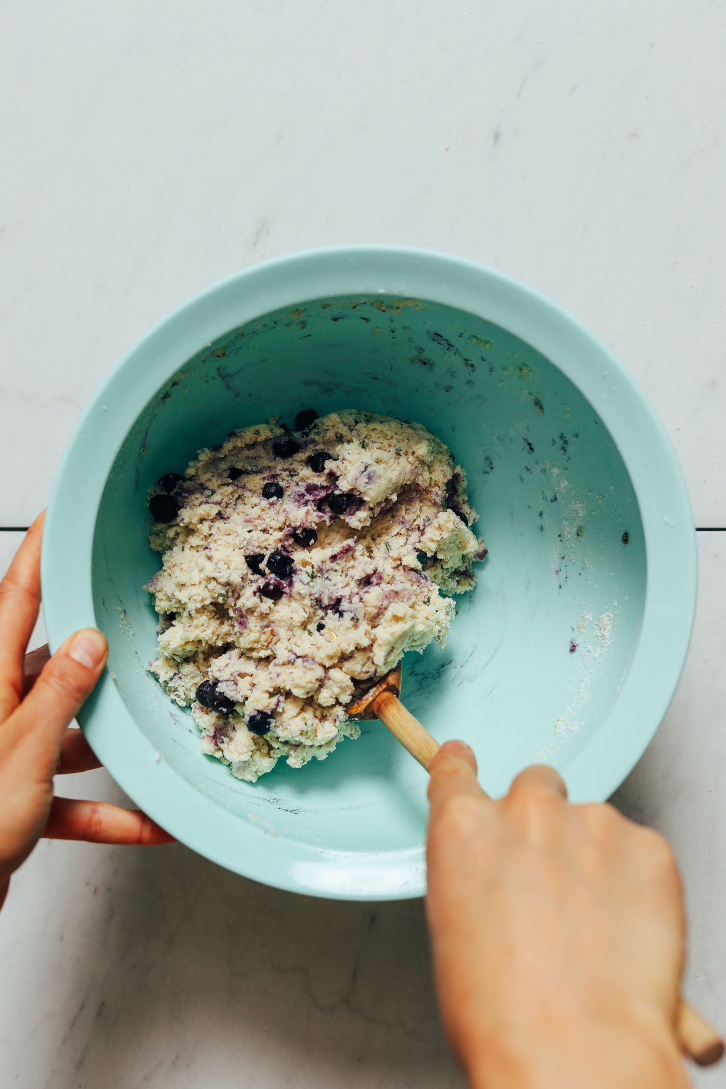 Using a wooden spoon to mix blueberries into Gluten Free Scone dough