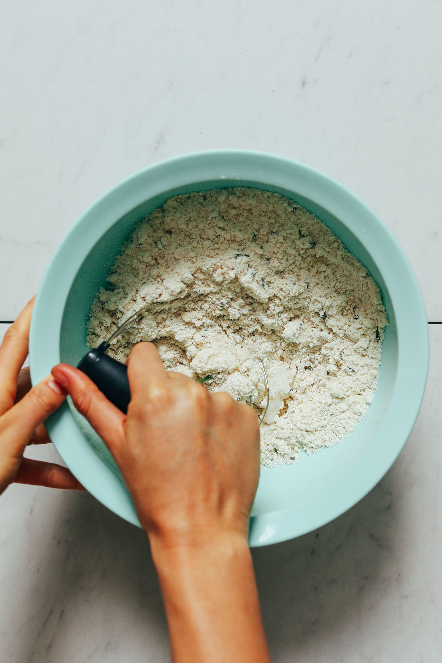 Using a pastry cutter to mix coconut oil into dry ingredients