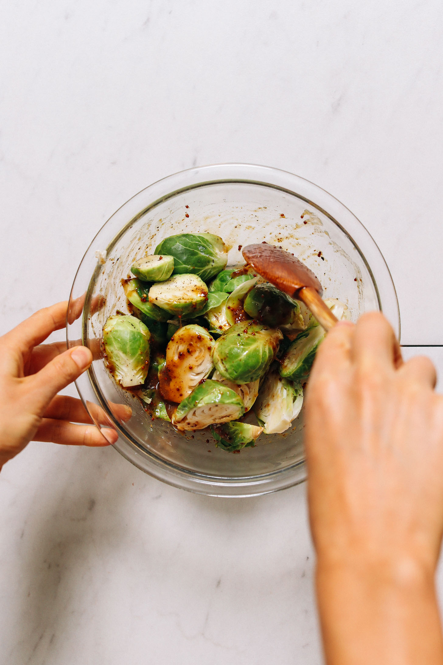 Stirring halved Brussels sprouts in a honey mustard dressing
