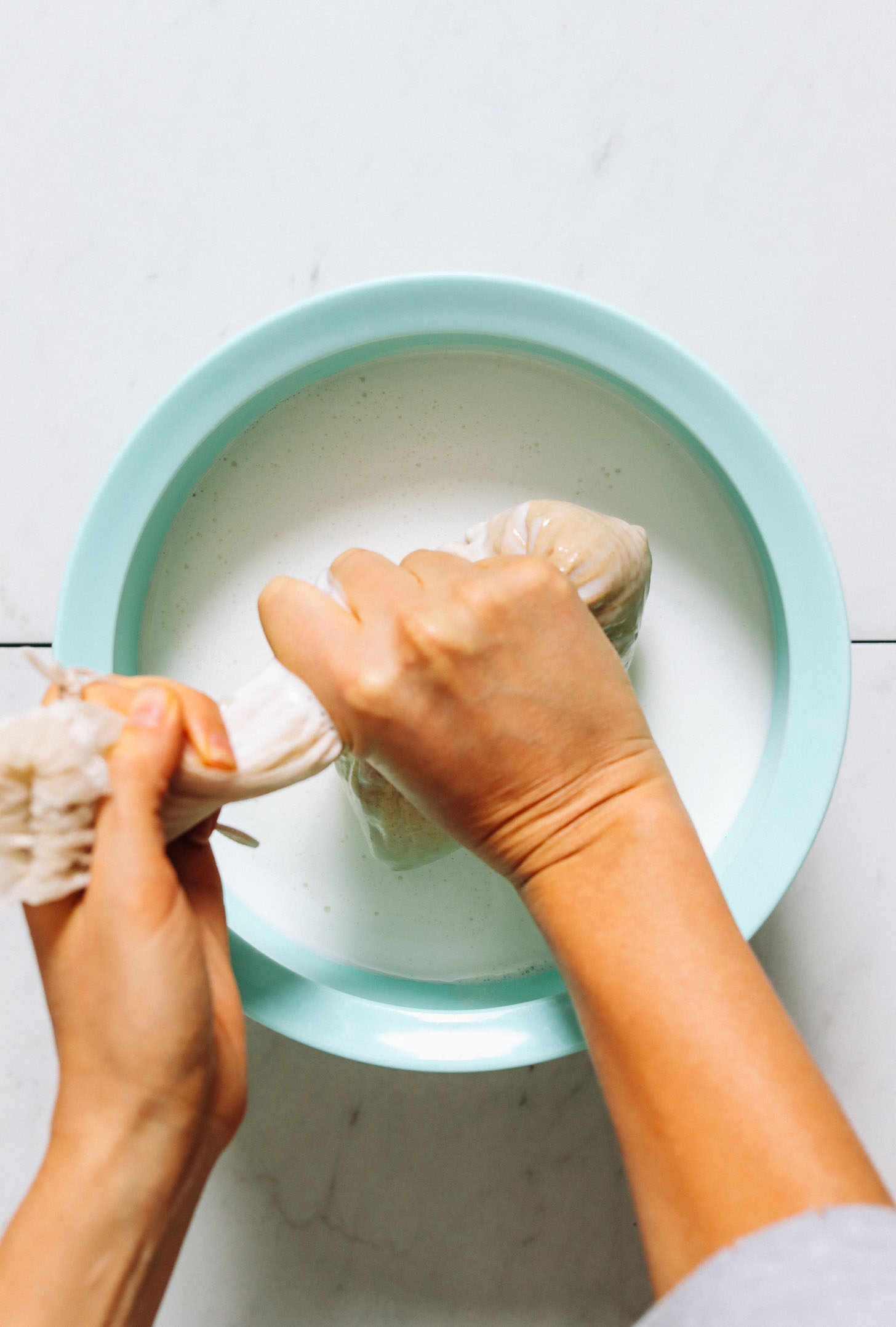 Squeezing coconut hemp pulp through a nut milk bag into a bowl
