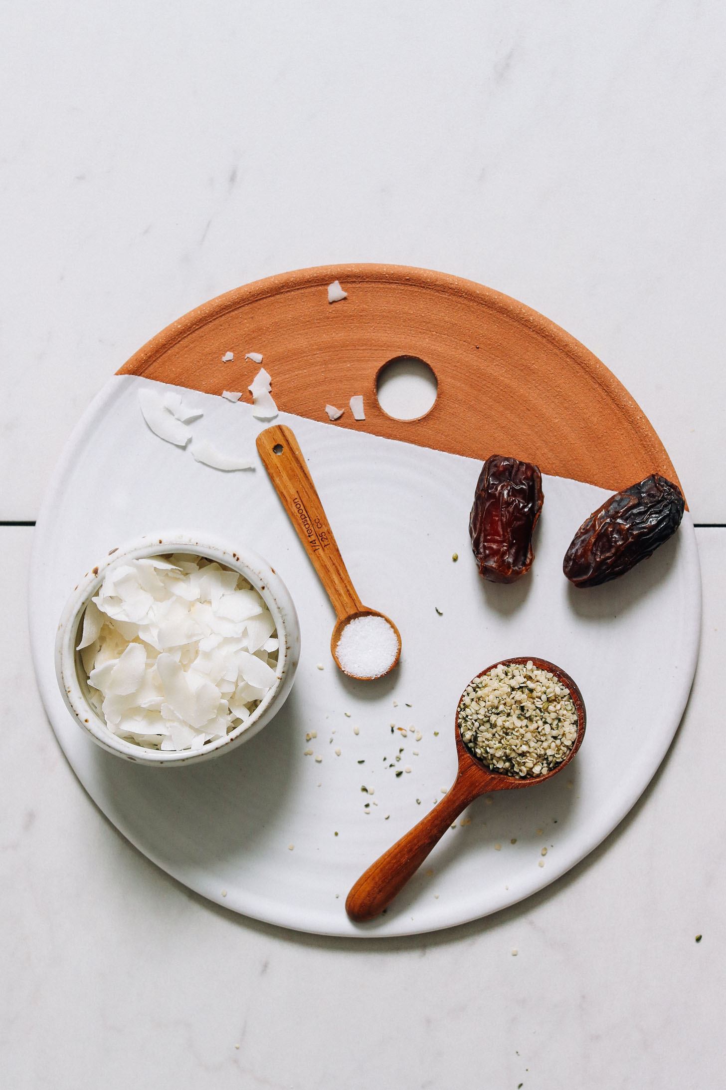 Tray of coconut flakes, hemp seeds, dates, and salt