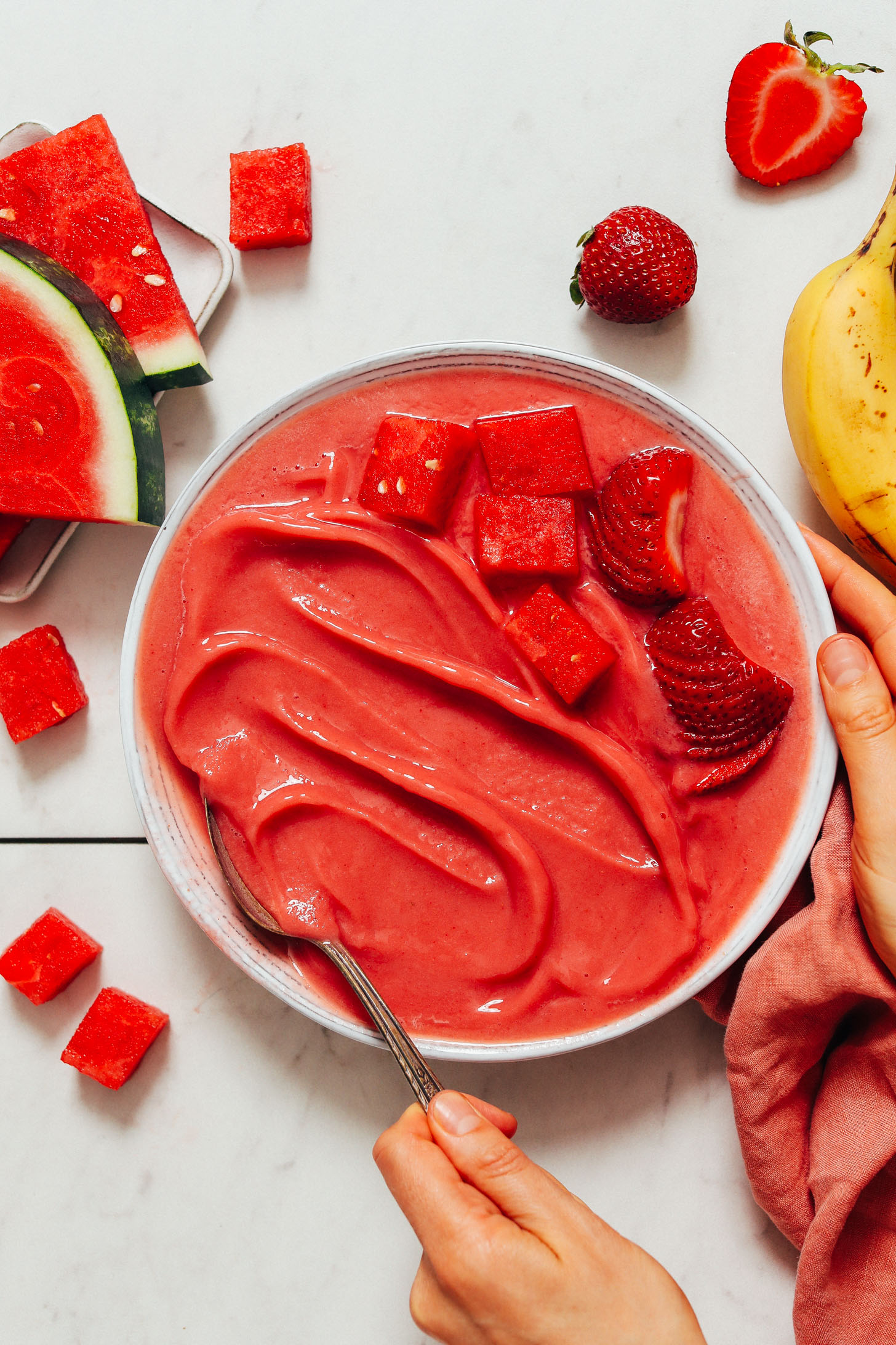Spoon in a bowl of Watermelon Sorbet topped with fresh strawberries and watermelon chunks