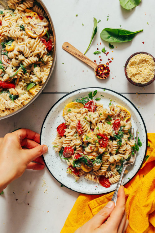 Fork resting on a plate of Creamy Vegan White Pasta with Summer Vegetables
