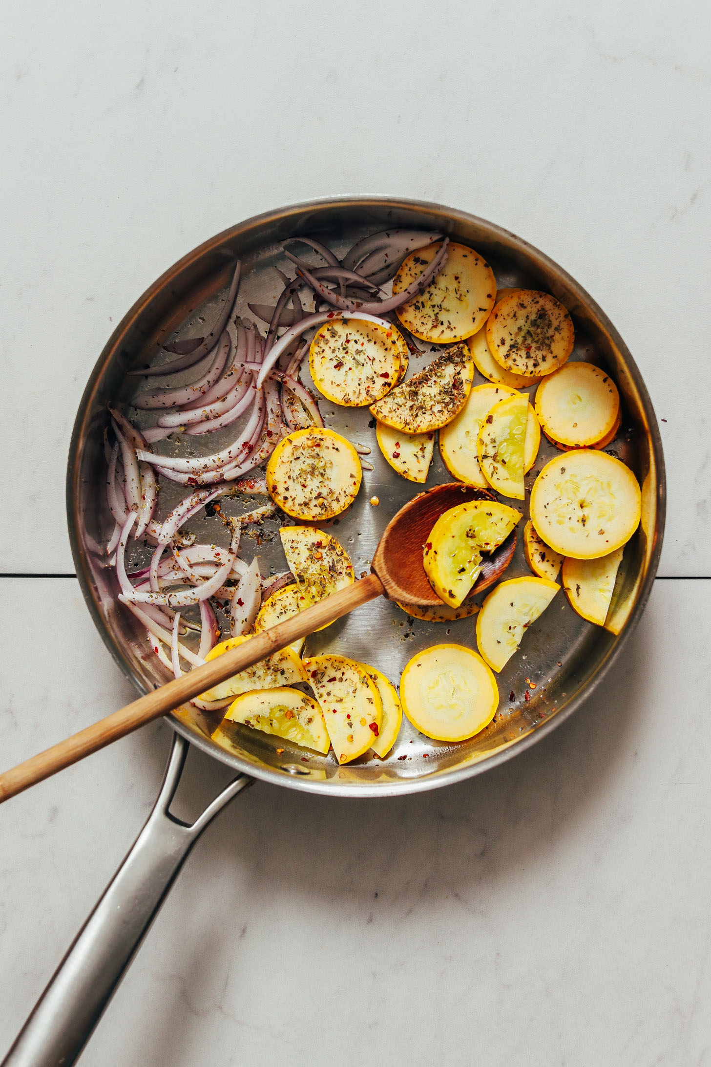 Sautéing yellow squash and red onion in a skillet with Italian seasonings