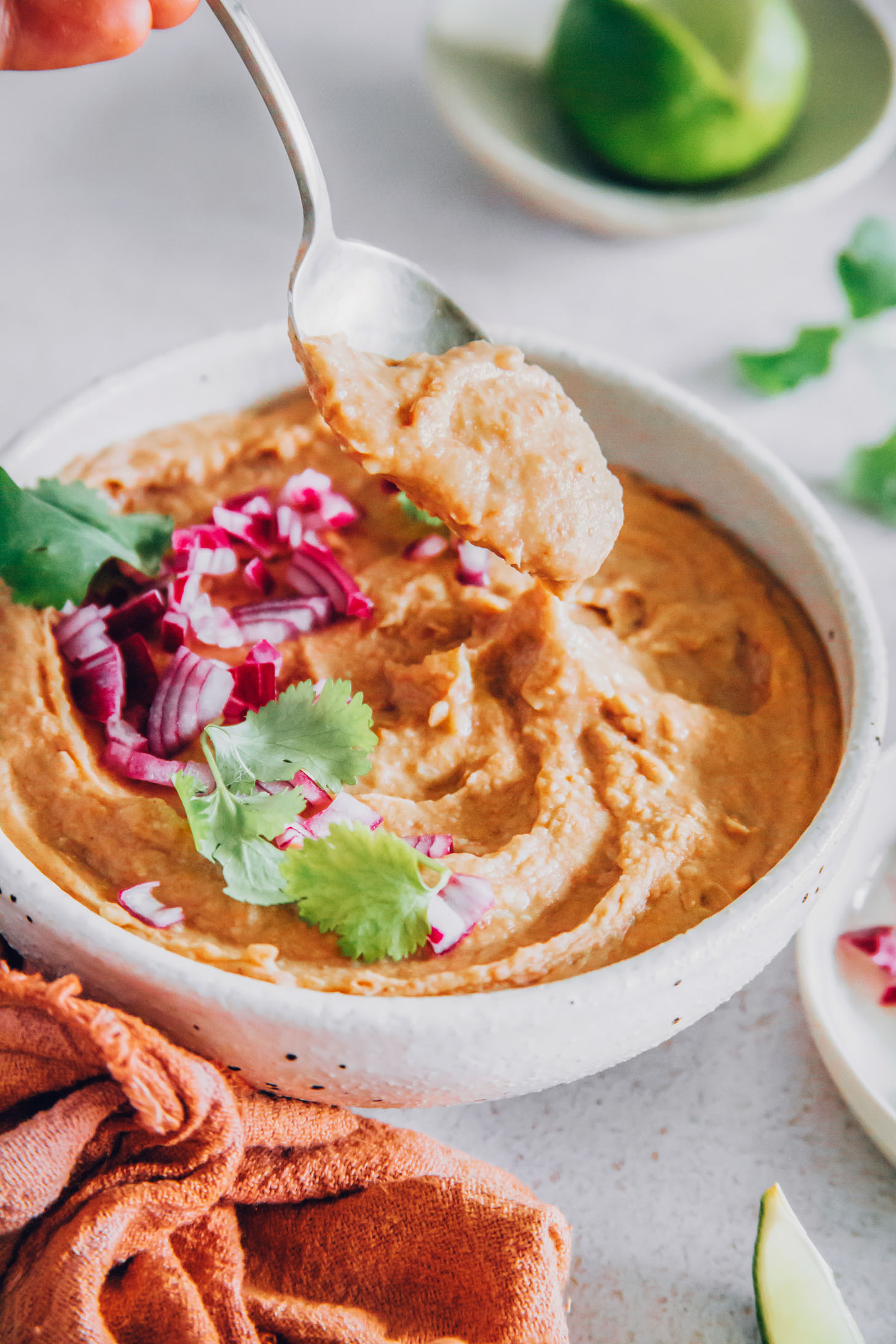 Spoonful of refried beans above a bowl