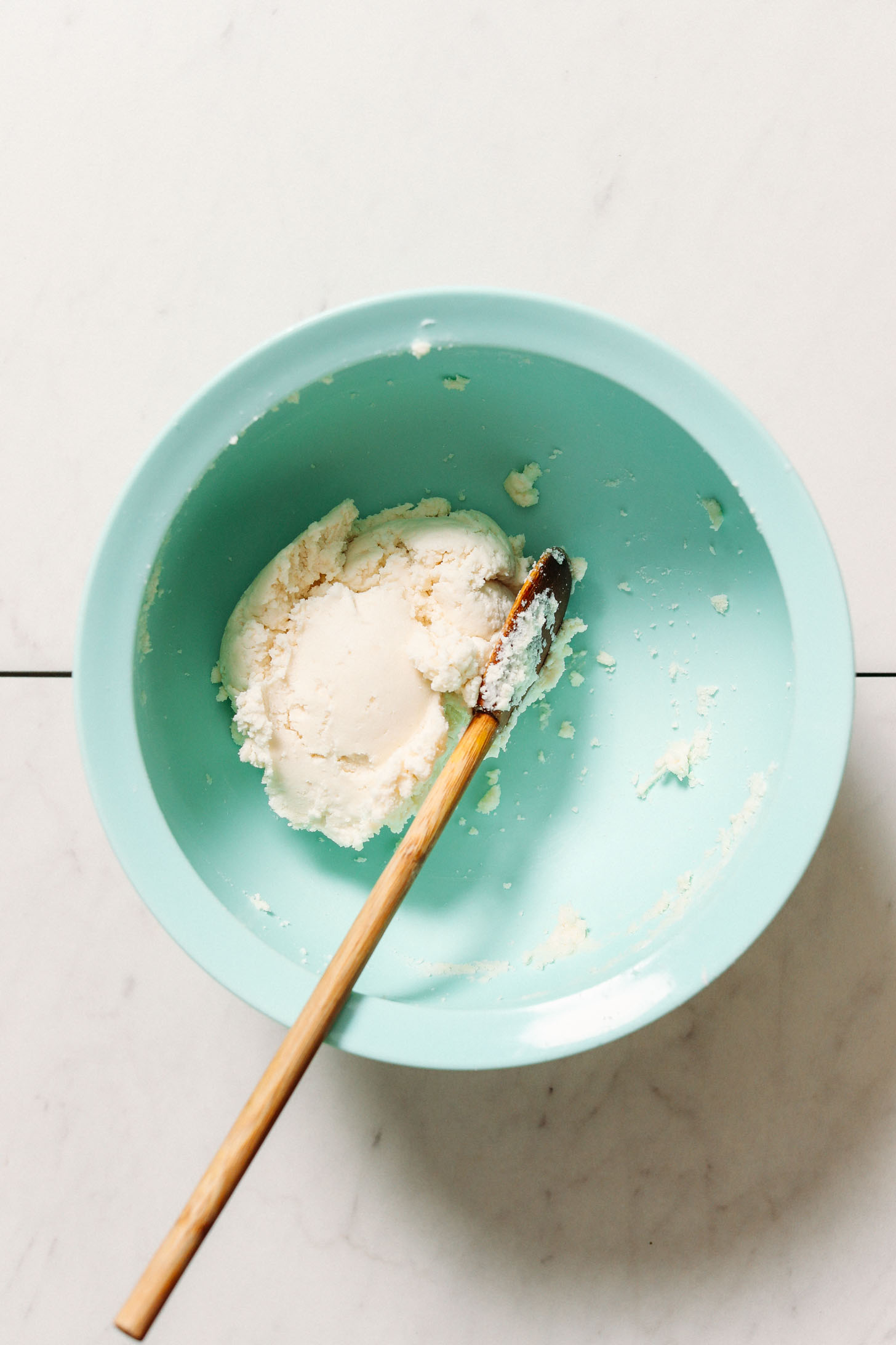 Wooden spoon in a bowl of gluten free naan dough