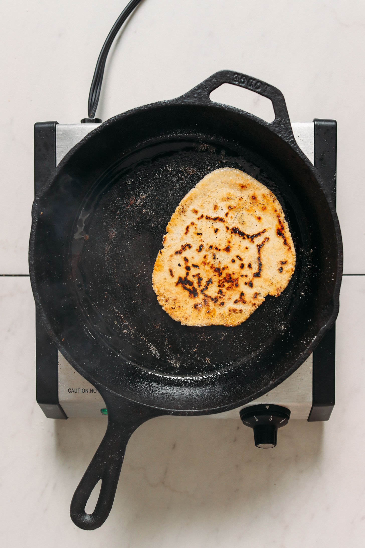 Cooking gluten free naan in a cast iron skillet
