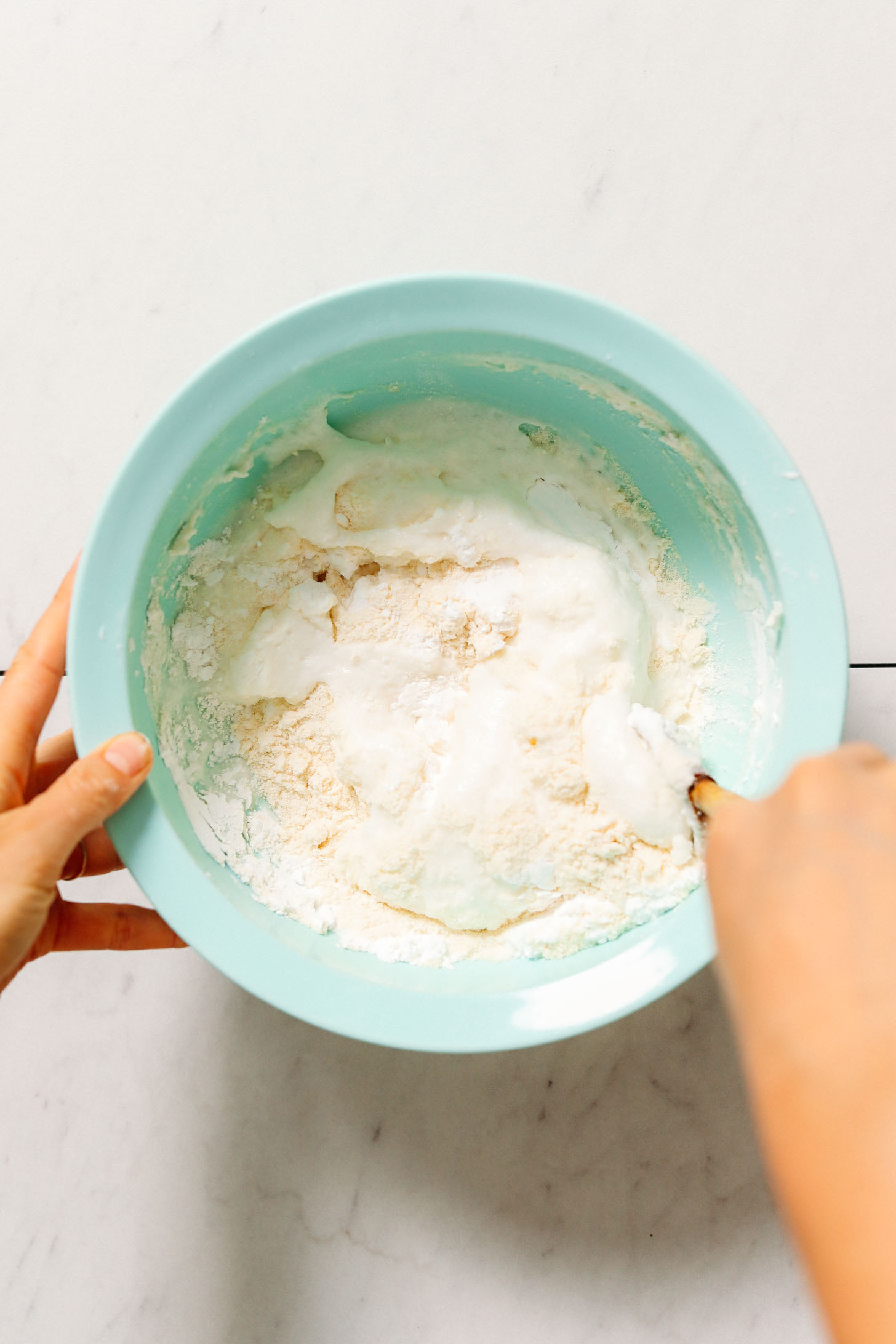 Using a wooden spoon to mix a bowl of naan dough