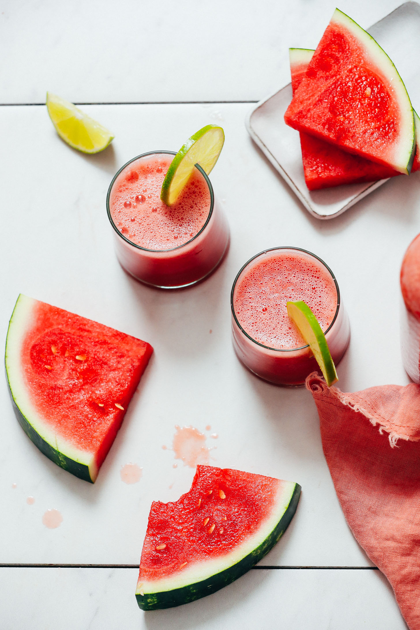 Watermelon slices next to two glasses of watermelon juice