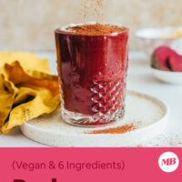 Sprinkling cacao powder over a glass of our red velvet cake smoothie recipe
