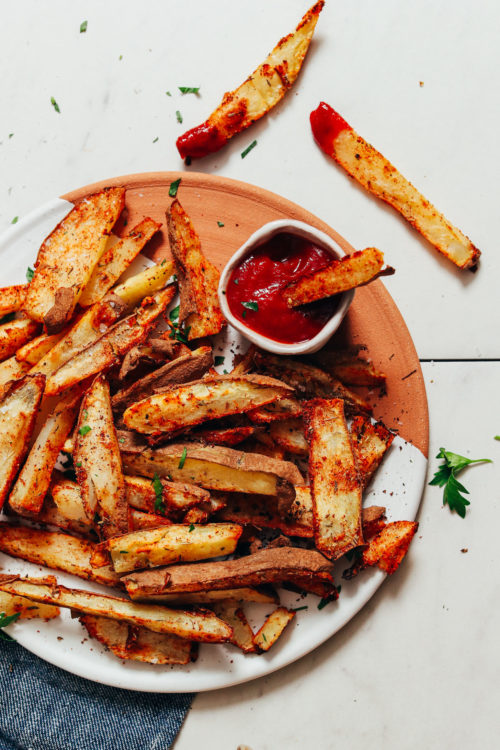 Clay and ceramic tray of Oil-Free Baked Fries seasoned with cajun seasonings