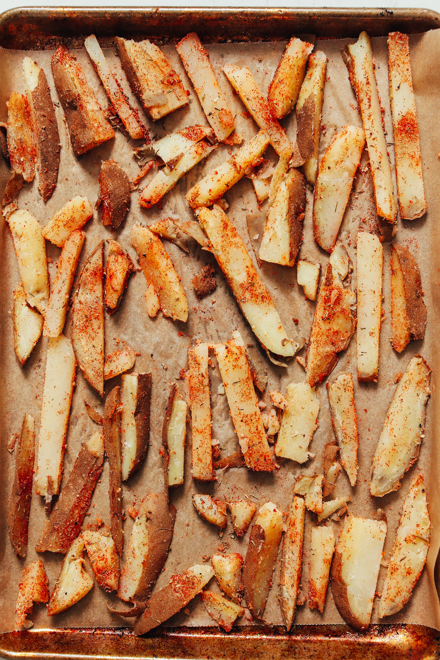Unbaked cajun fries on a parchment-lined baking sheet