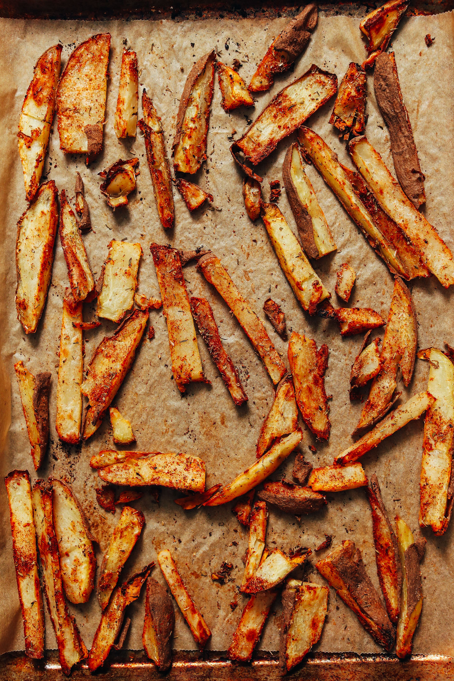 Parchment-lined baking sheet of oil-free fries with cajun seasonings