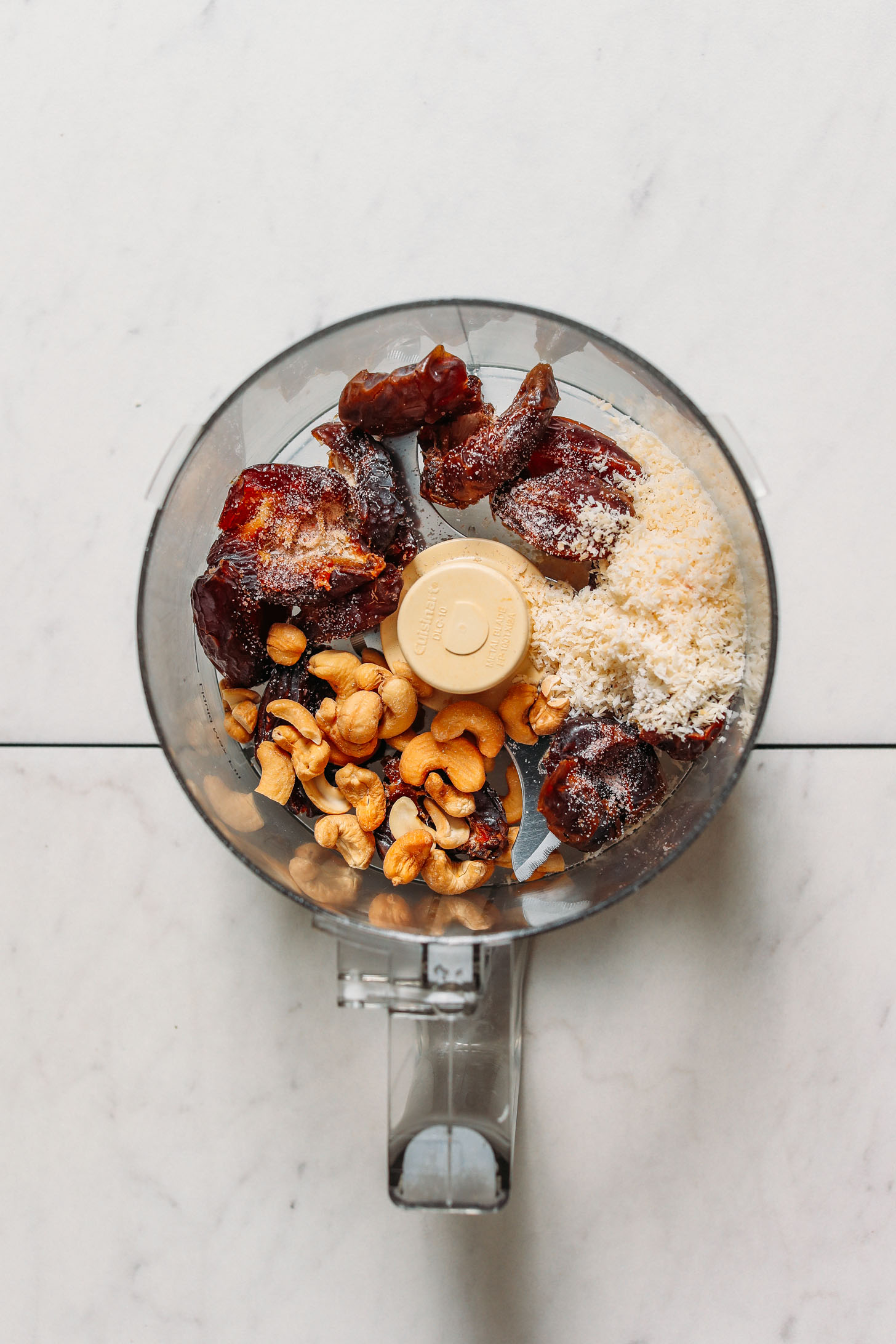 Food processor with pitted dates, shredded coconut, cashews, and sea salt