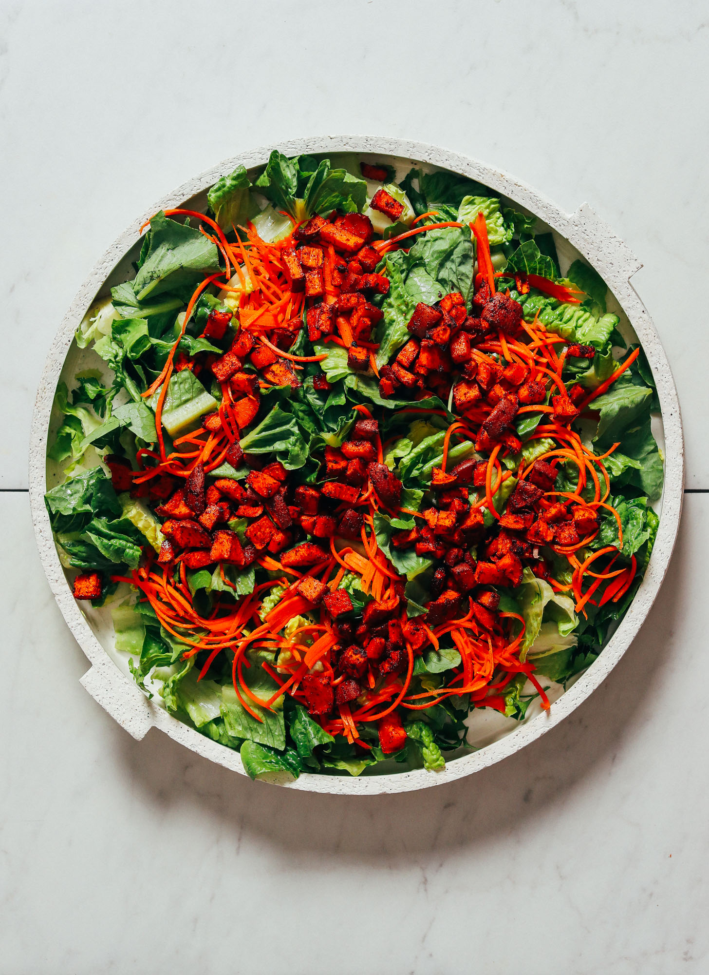 Platter of romaine lettuce topped with shredded carrots and BBQ Sweet Potato Croutons