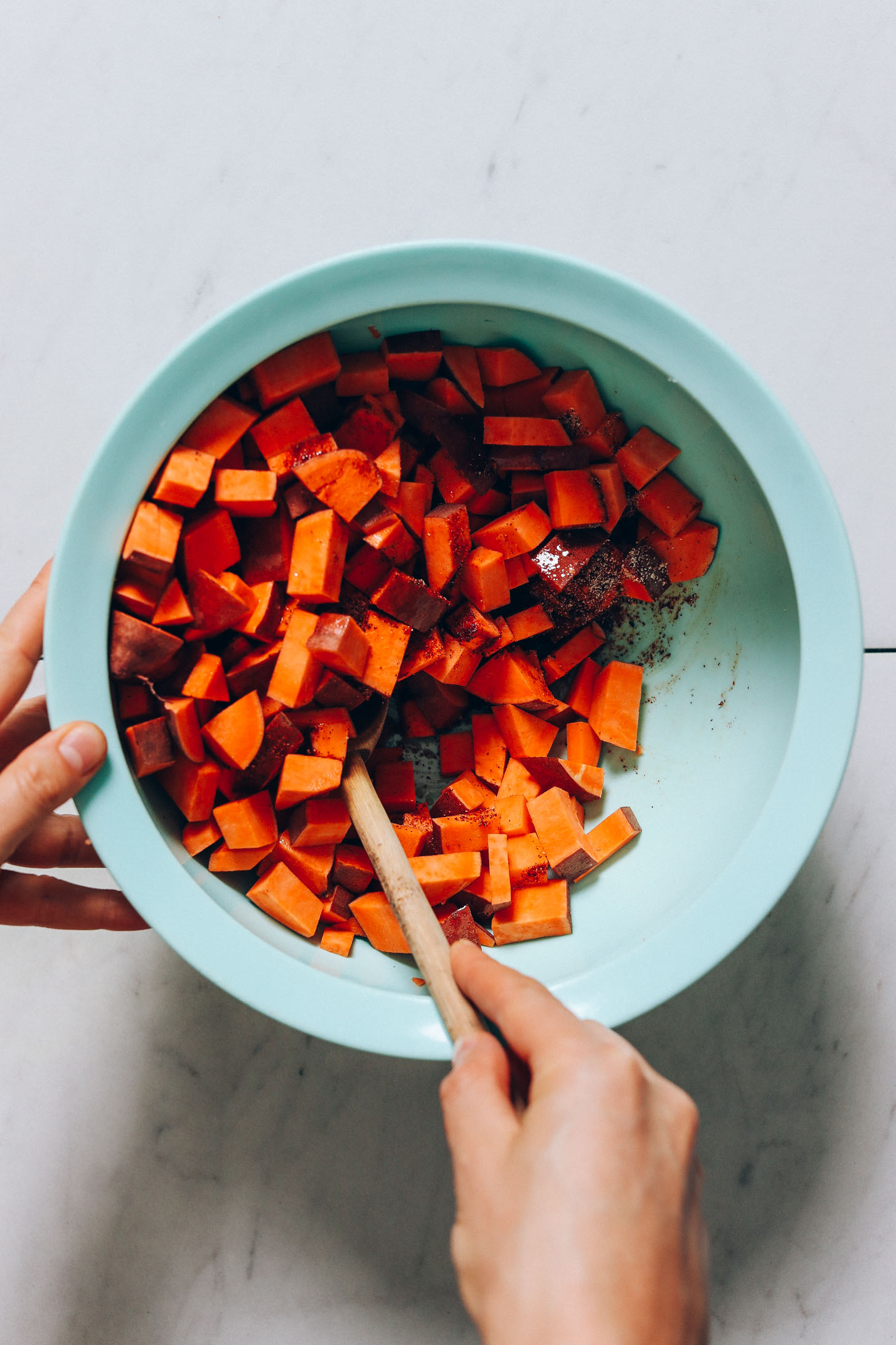 Stirring cubed sweet potatoes with oil and BBQ spices