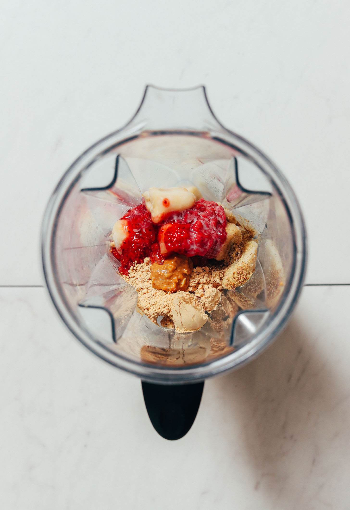 Blender with peanut butter, banana, peanut butter powder, and strawberry compote
