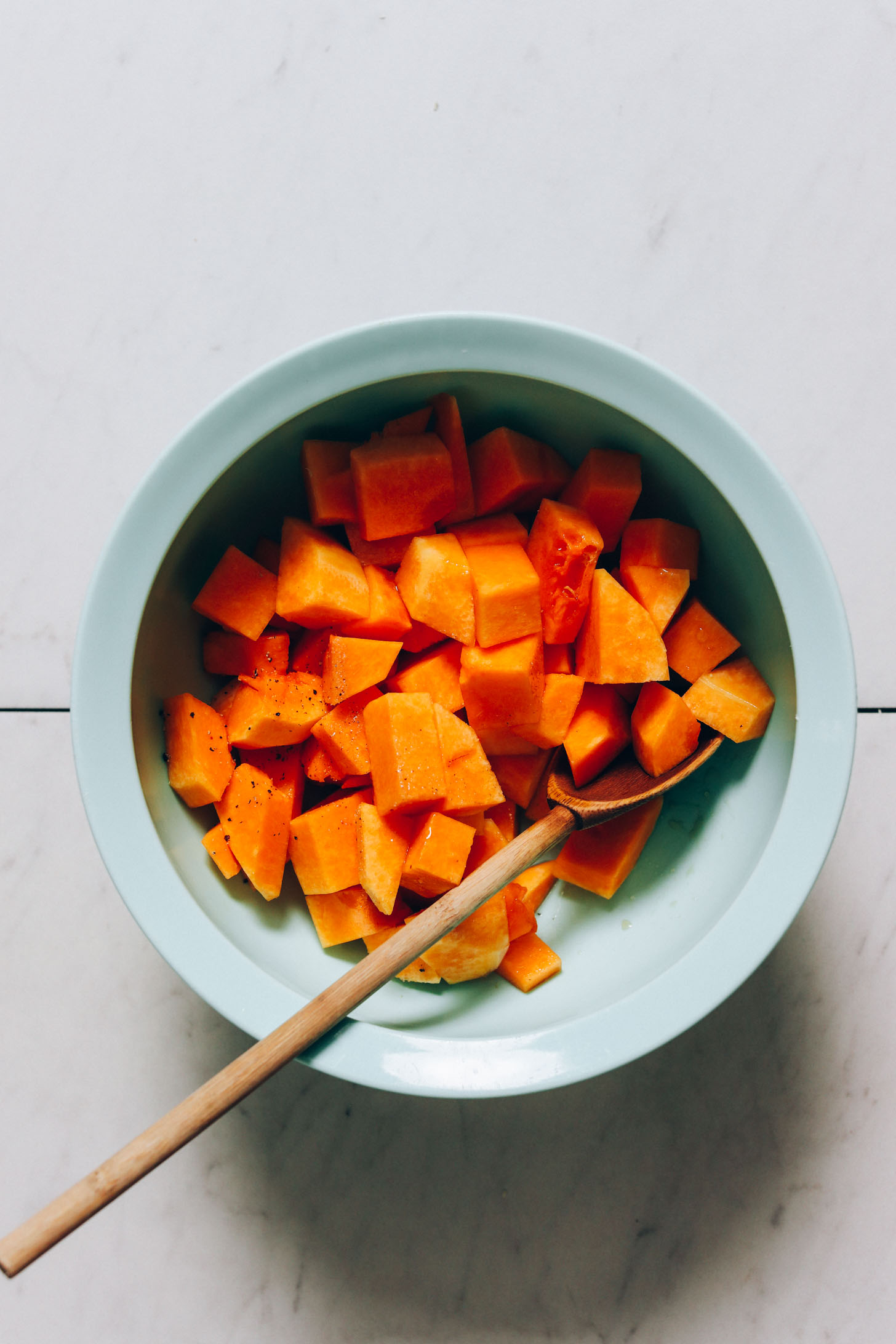 Bowl of butternut squash, avocado oil, maple syrup, sea salt, and black pepper