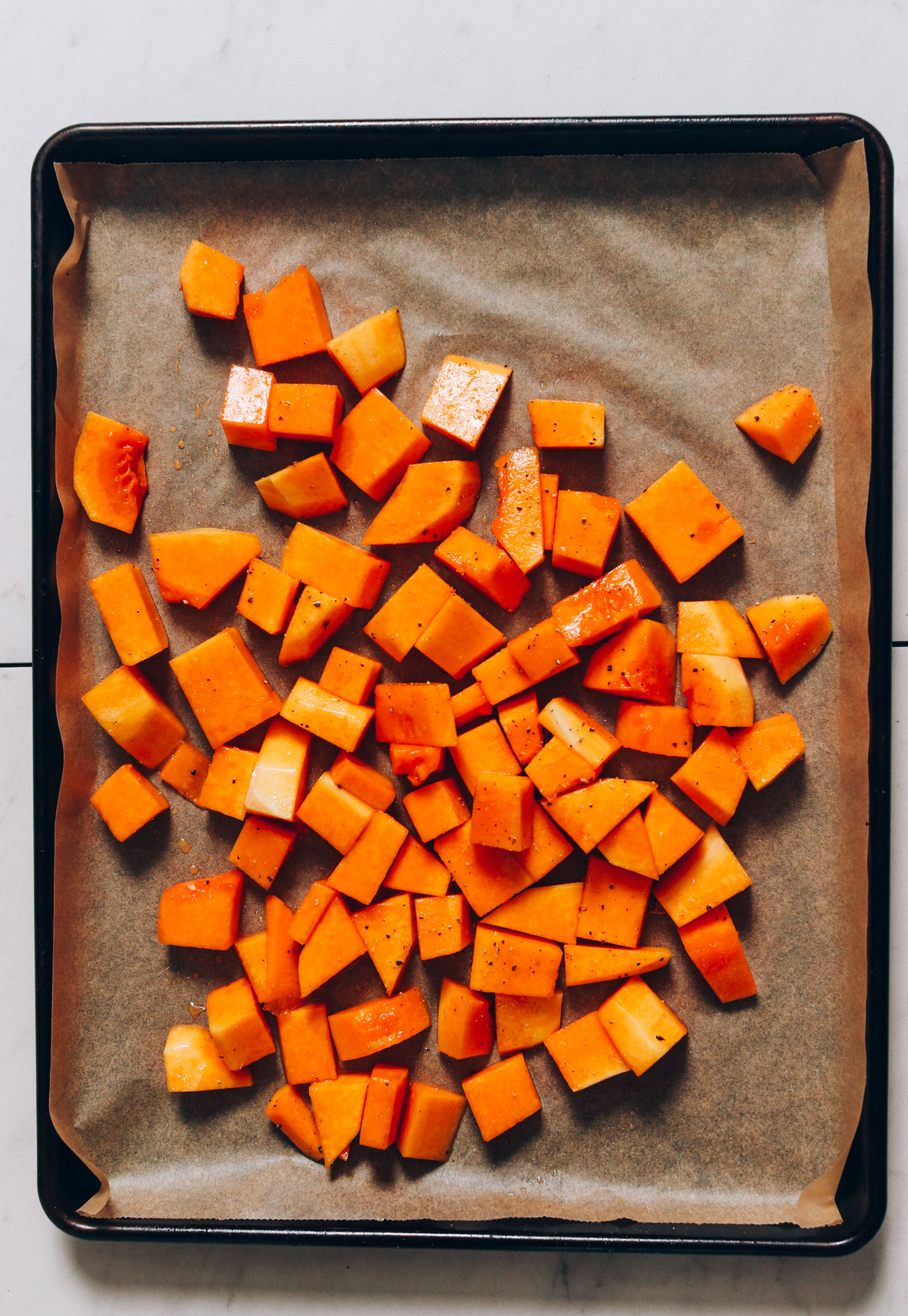 Cubed butternut squash seasoned with avocado oil, maple syrup, salt, and pepper