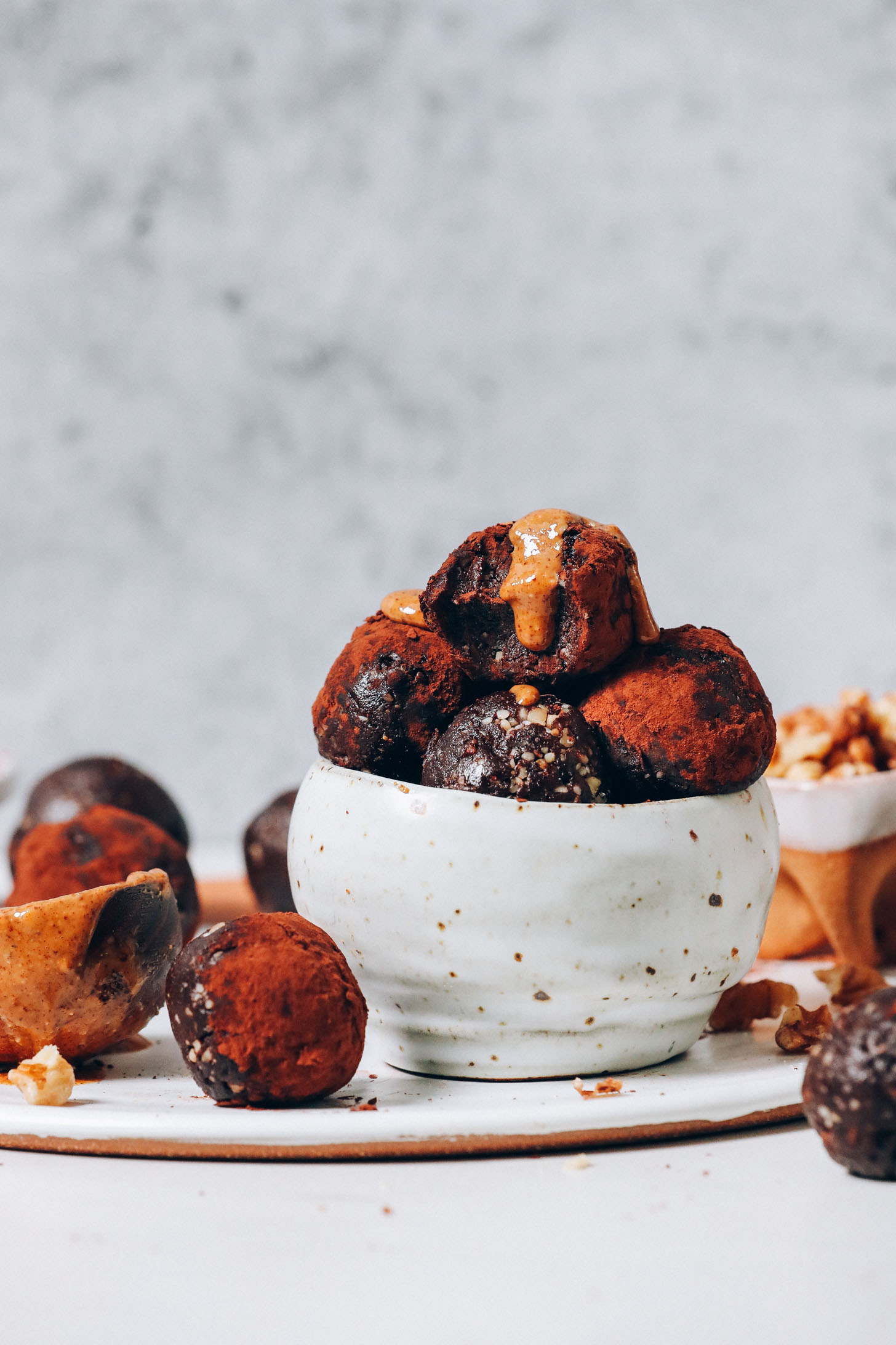 Walnuts and almond butter next to a bowl of No Bake Brownie Bites