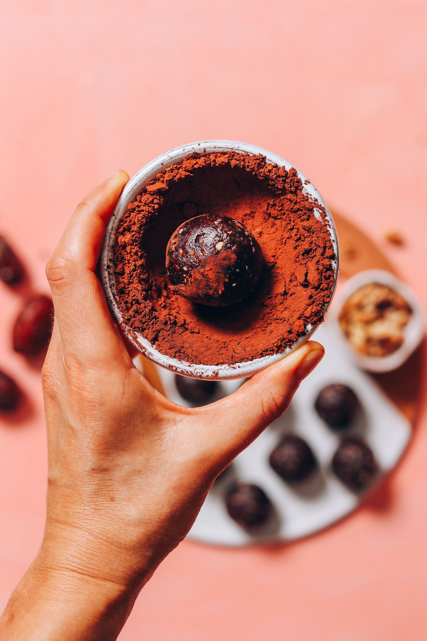No Bake Brownie Bite rolled in a bowl of cacao powder