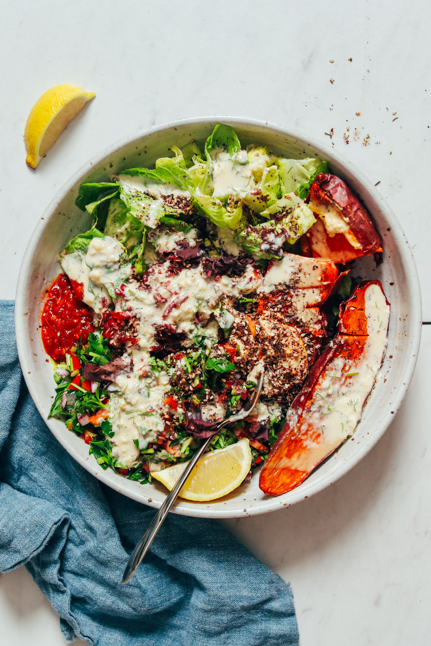 Spoon resting in a Nourish Bowl made with sweet potato, romaine, parsley, and garlic dill sauce