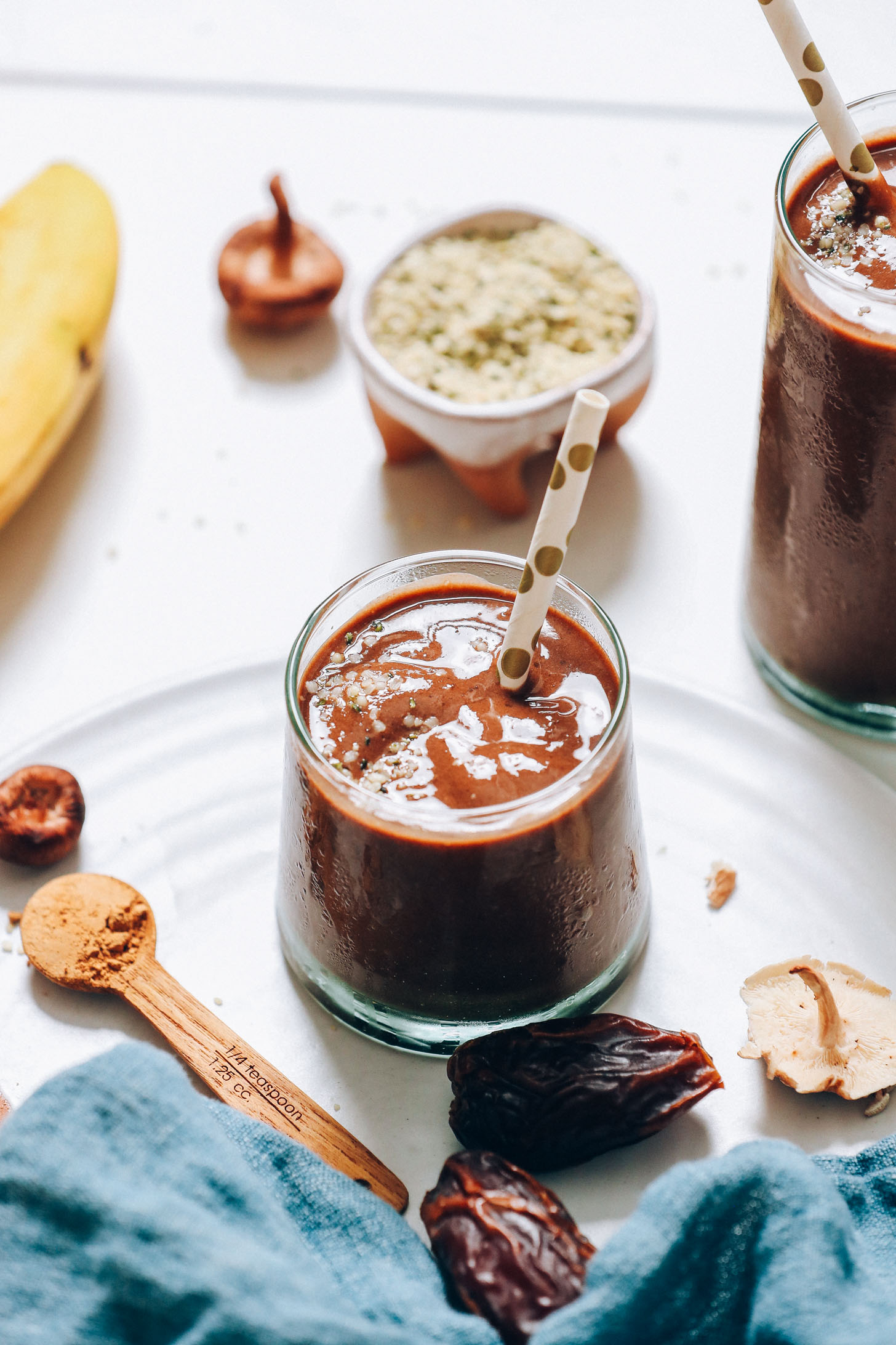 Chocolate Banana Adaptogen Shake next to dates, shiitake mushrooms, hemp seeds, and maca