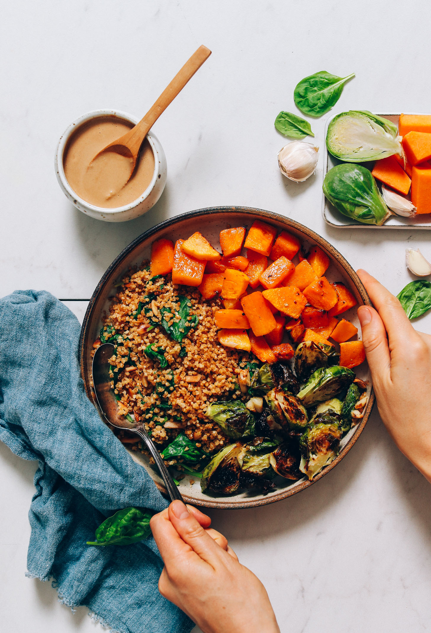 Holding the side of a Butternut Squash & Miso Brussels Sprouts Nourish Bowl