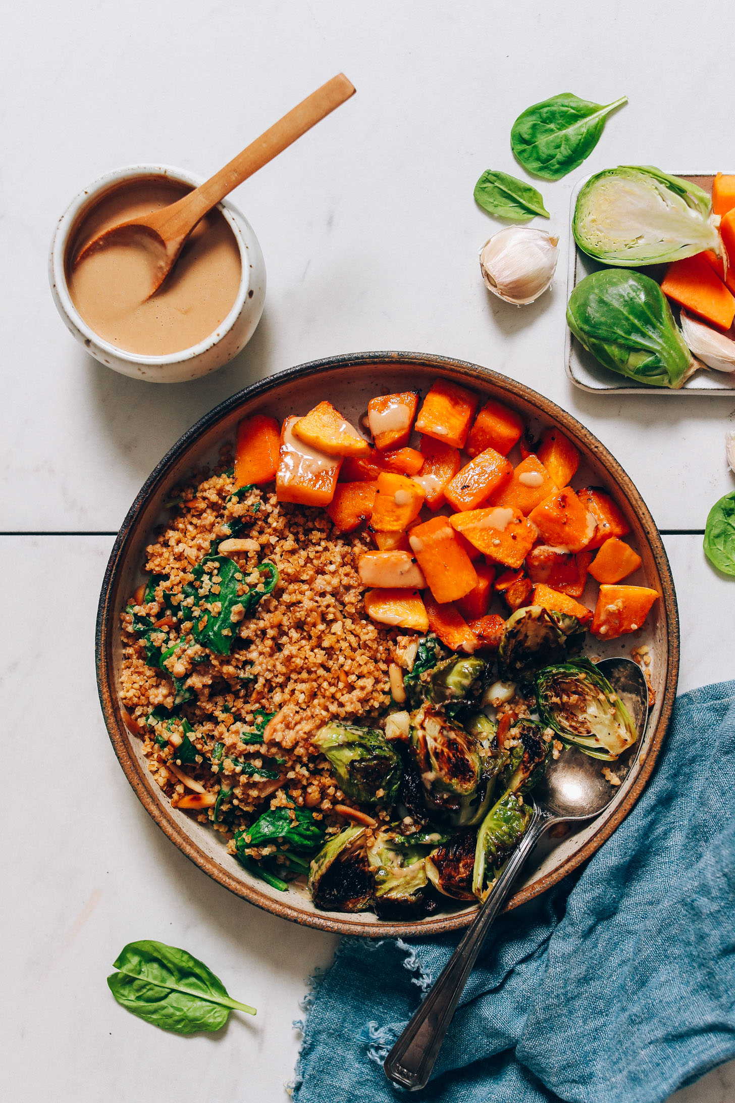 Fall nourish bowl made with squash, brussels sprouts, millet, and garlicky tahini sauce